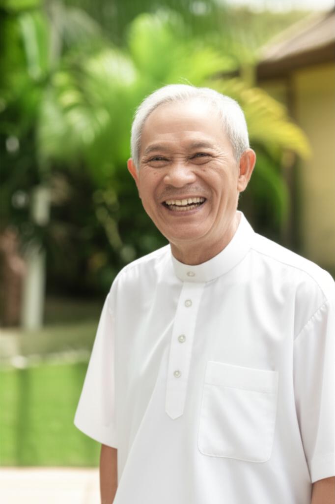 A smiling Malaysian man, Ahmad, looking vibrant and active, perhaps playing with grandchildren or enjoying a walk outdoors, showing improved health and vitality.